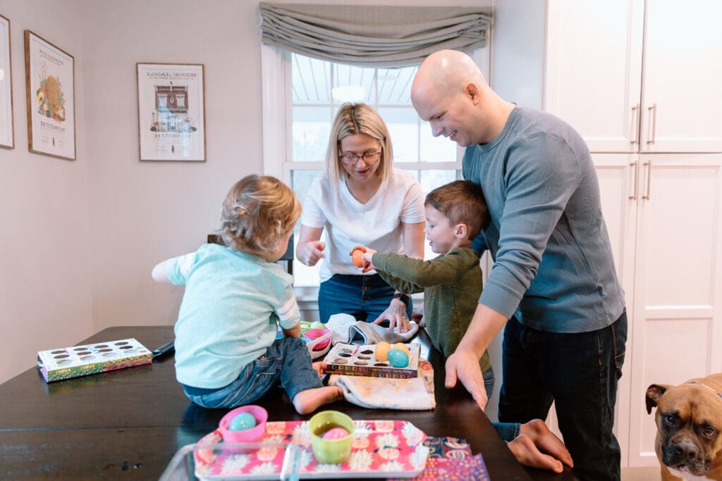 Family of four decorating Easter eggs.