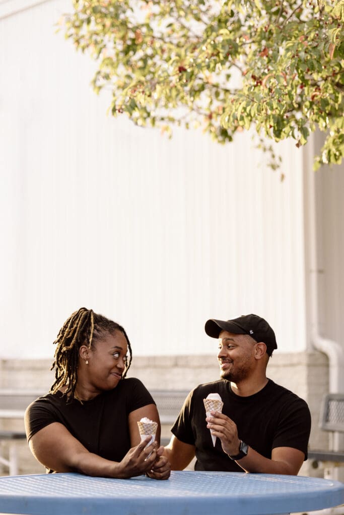 Couple smiling at each other while holding ice cream.