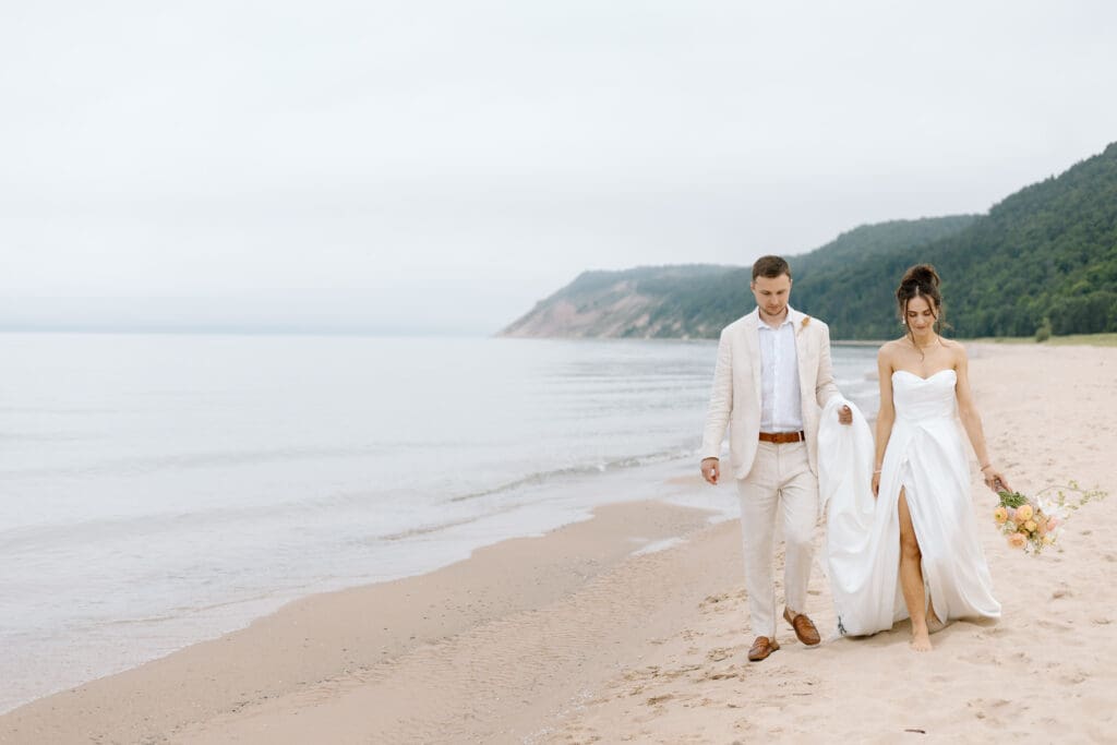 Couple walking along the beach during an early morning elopement in Northern Michigan.