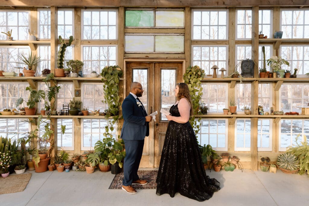 Couple saying vows in a greenhouse during a winter elopement in Ohio.