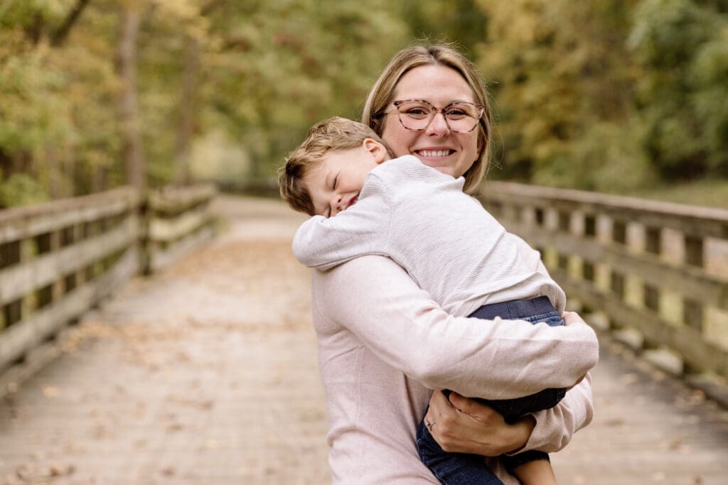 Mother hugging her son and smiling at the camera.