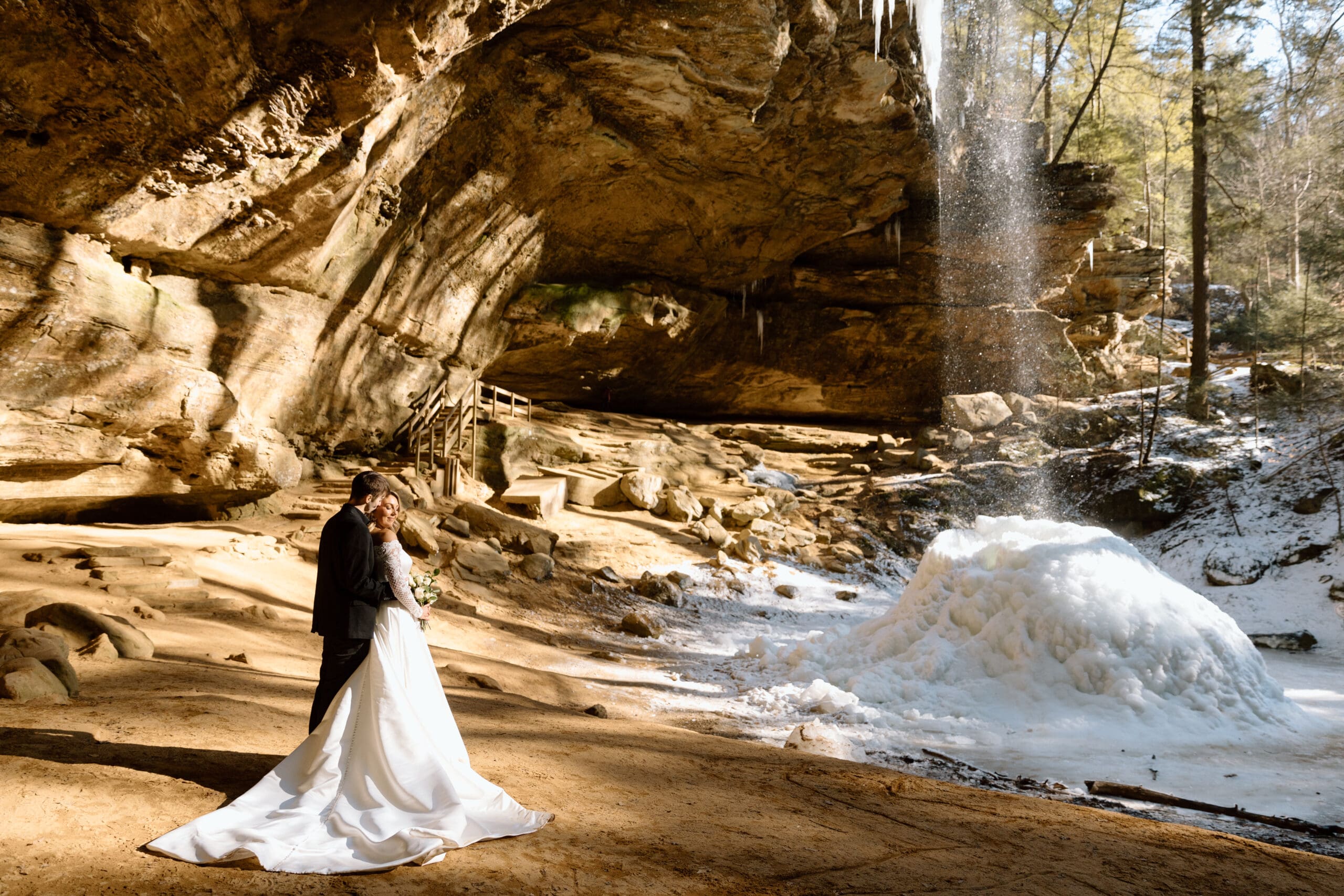 Couple standing in front of Ash Cave's waterfall.