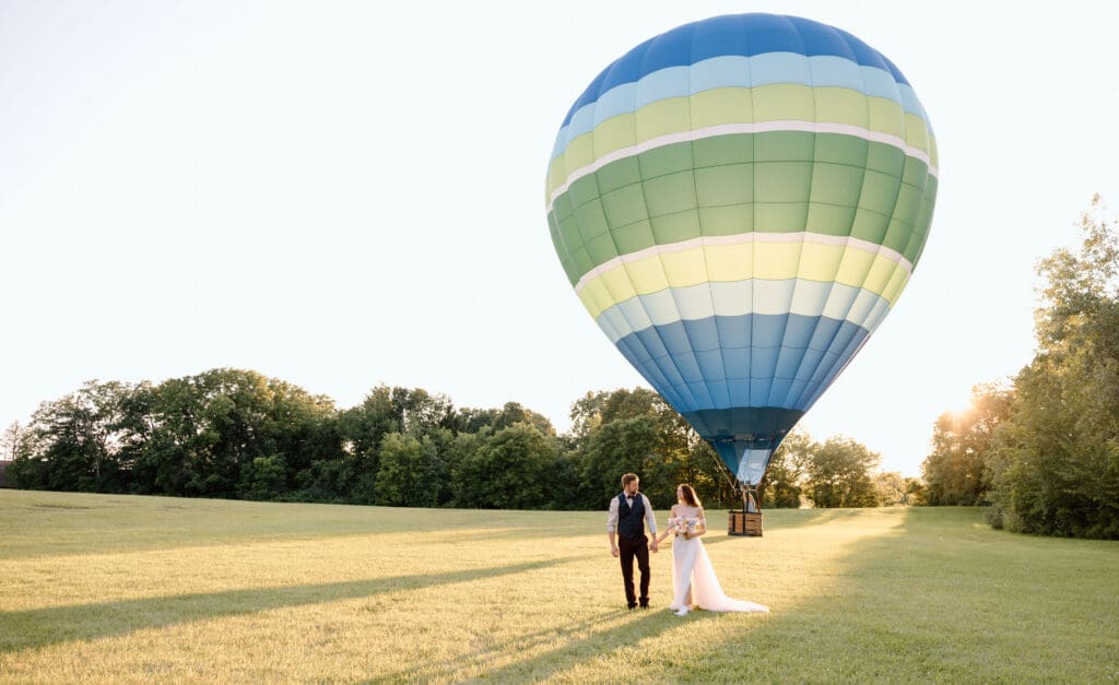 Couple walking away from a hot air balloon.