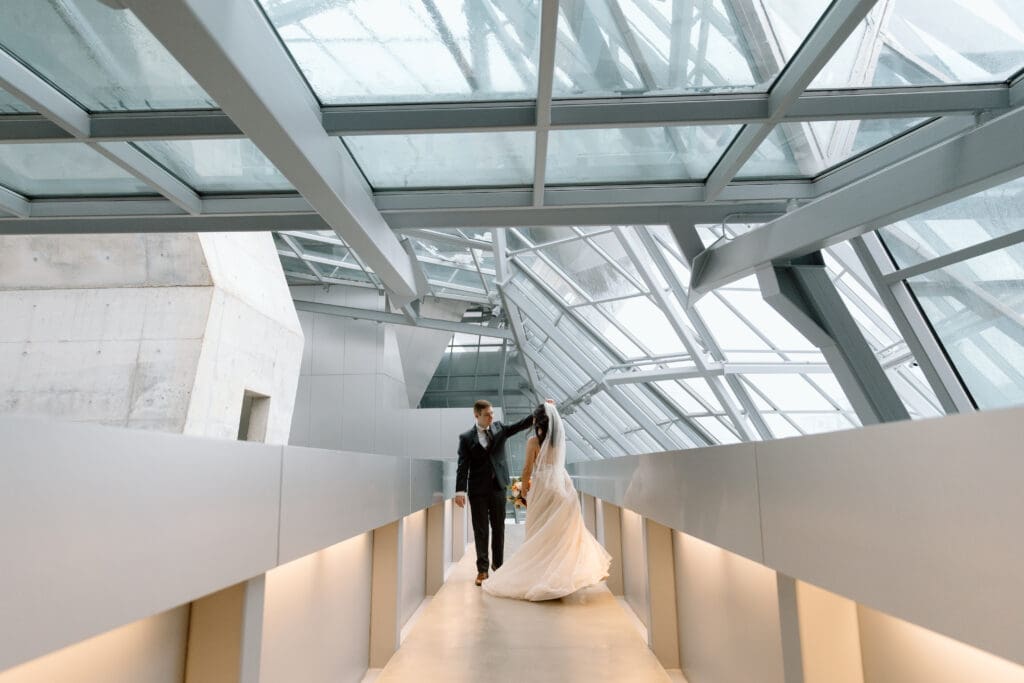 Groom spinning bride in Akron Art Museum during a winter elopement in Akron, Ohio.