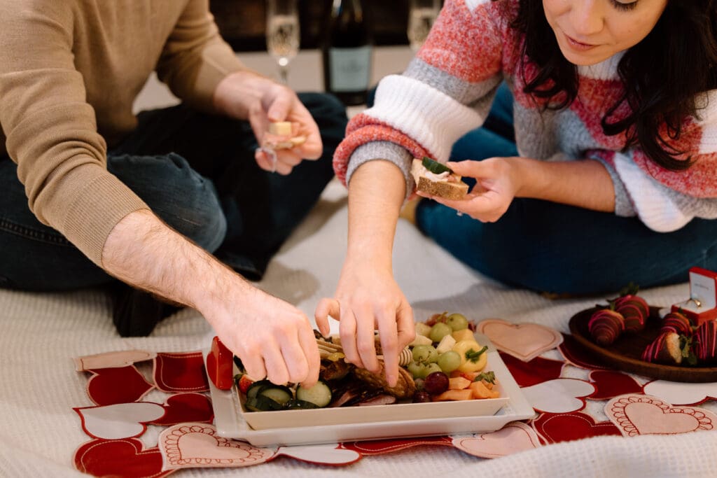 Couple grabbing food off a charcuterie board.