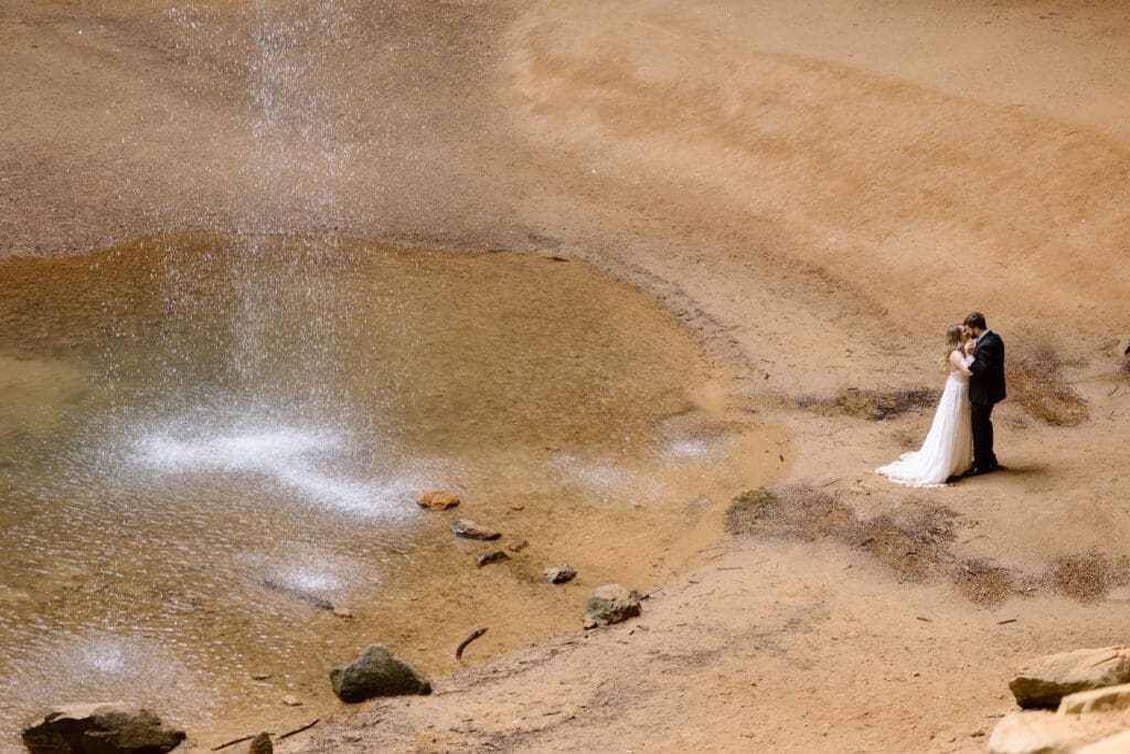 Couple kissing next to the waterfall at Ash Cave, taken from a high angle.