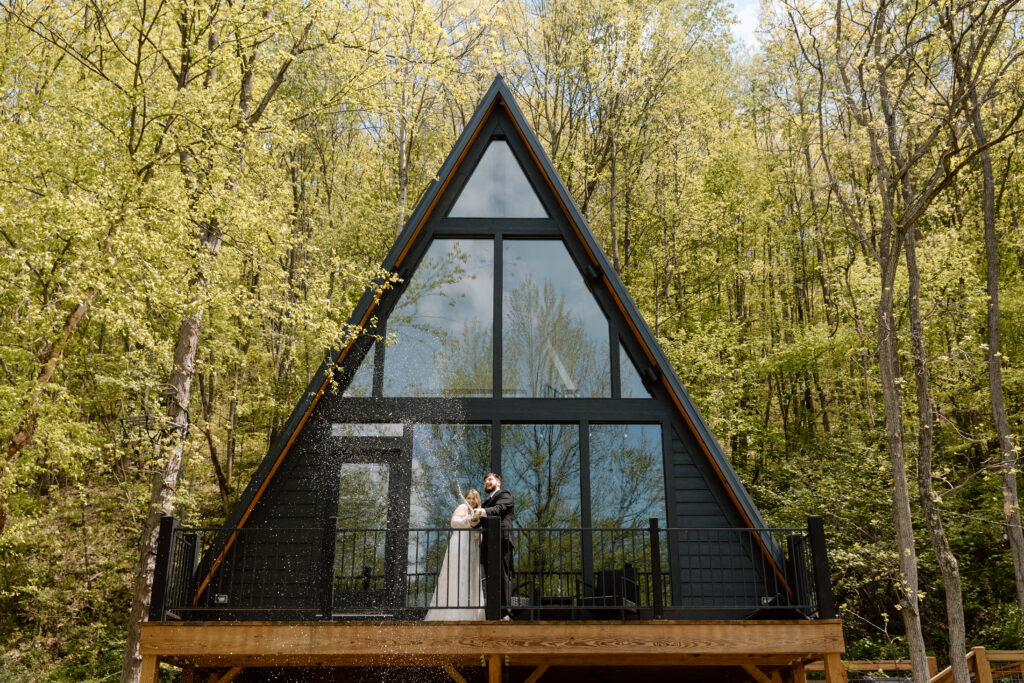 Couple popping champagne at an a-frame cabin in Hocking Hills.