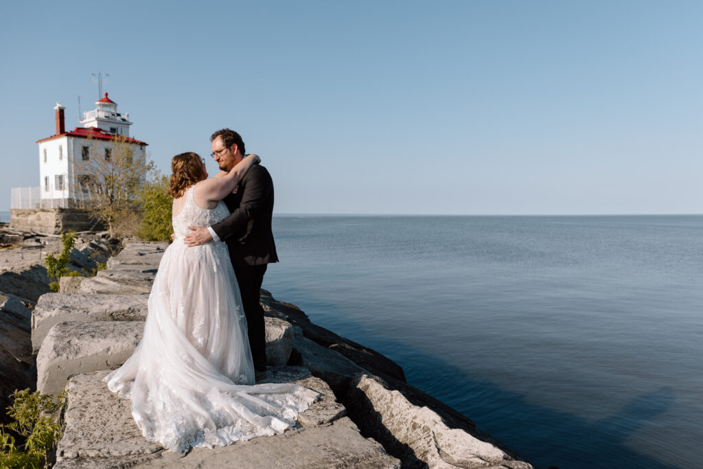 Eloping couple embracing at Headlands Beach State Park's lighthouse.