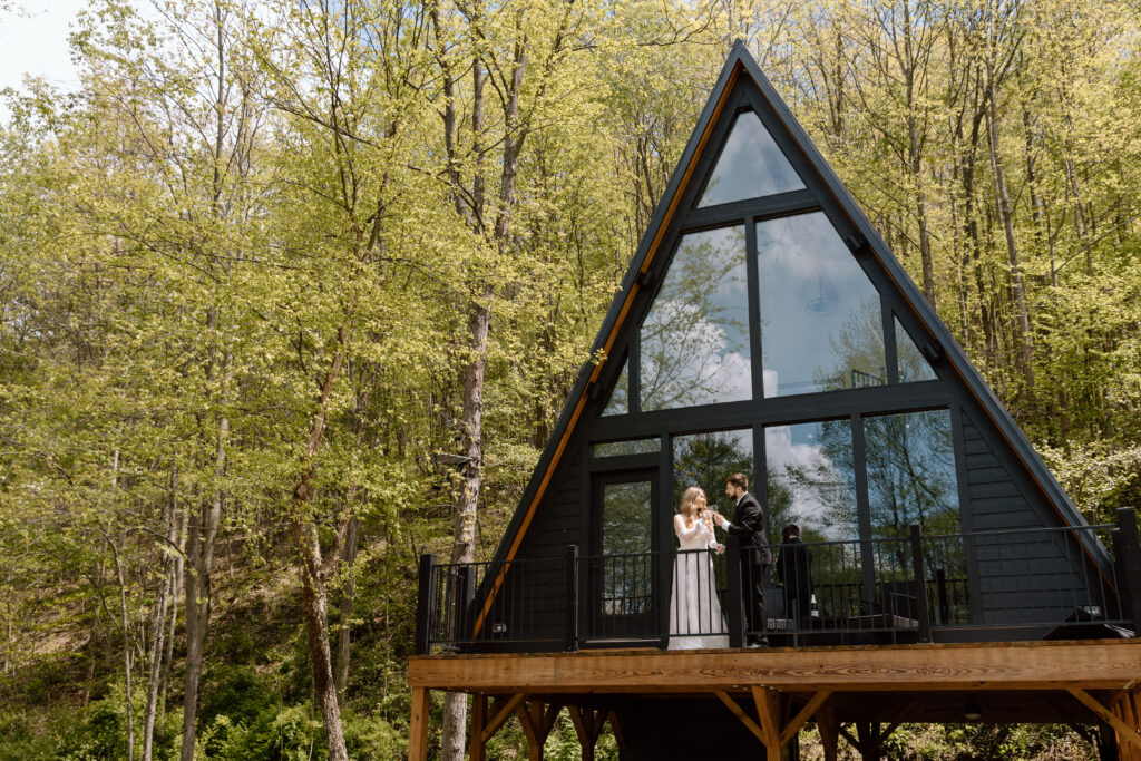 Couple toasting with champagne outside of their A-Frame airbnb.