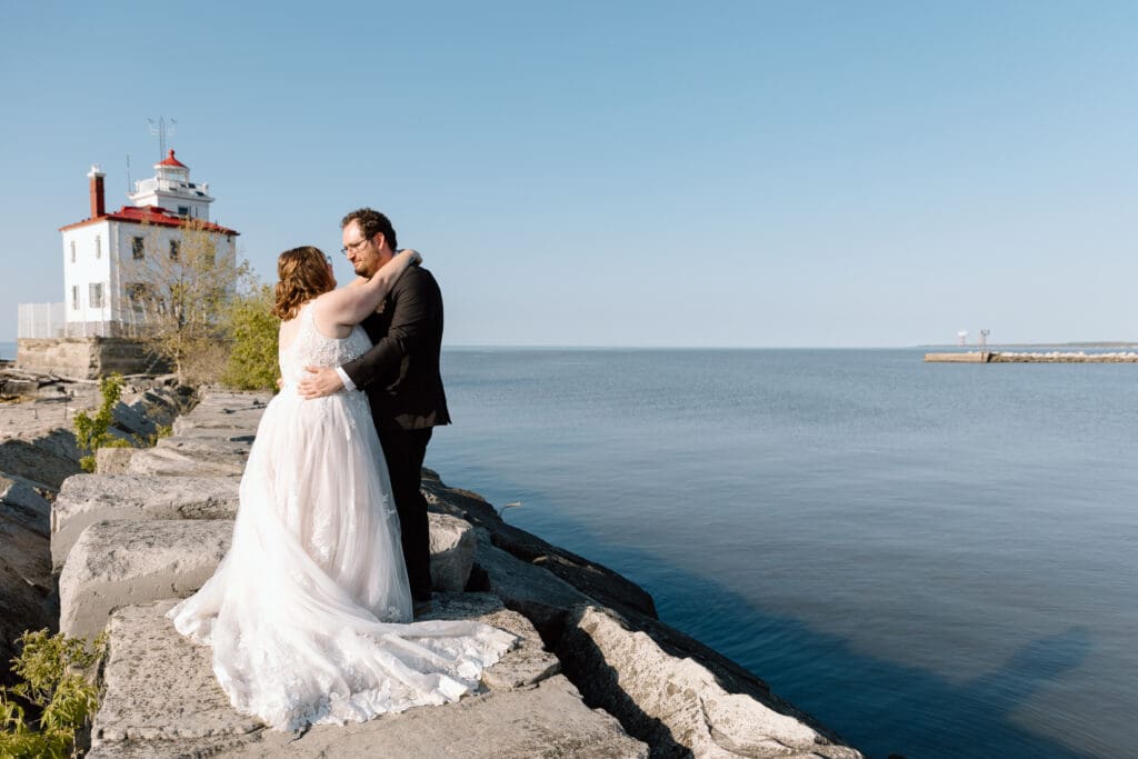 Eloping couple embracing in front of the Headlands Beach State Park lighthouse.