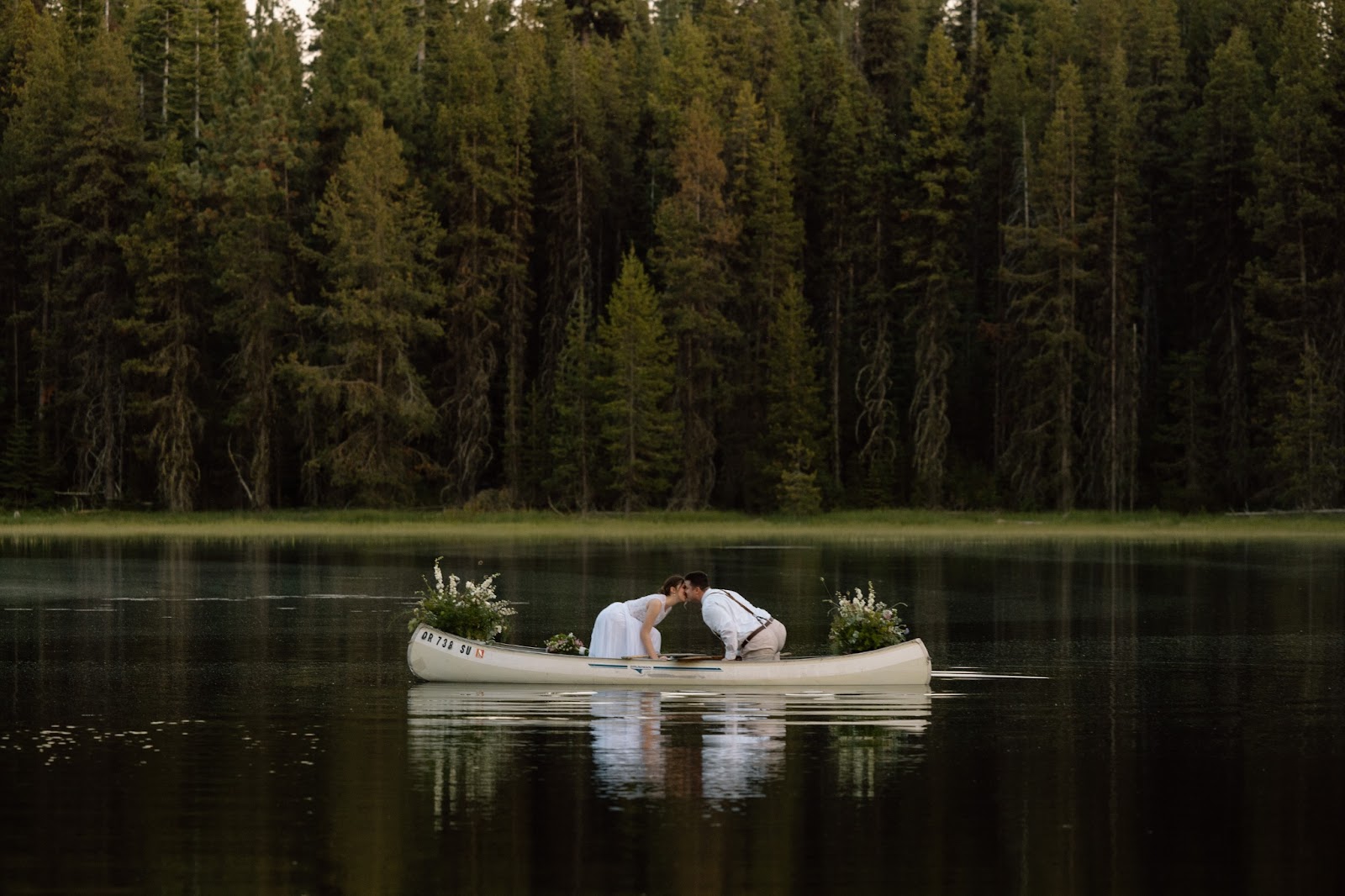 Couple leaning over for a kiss in a canoe.