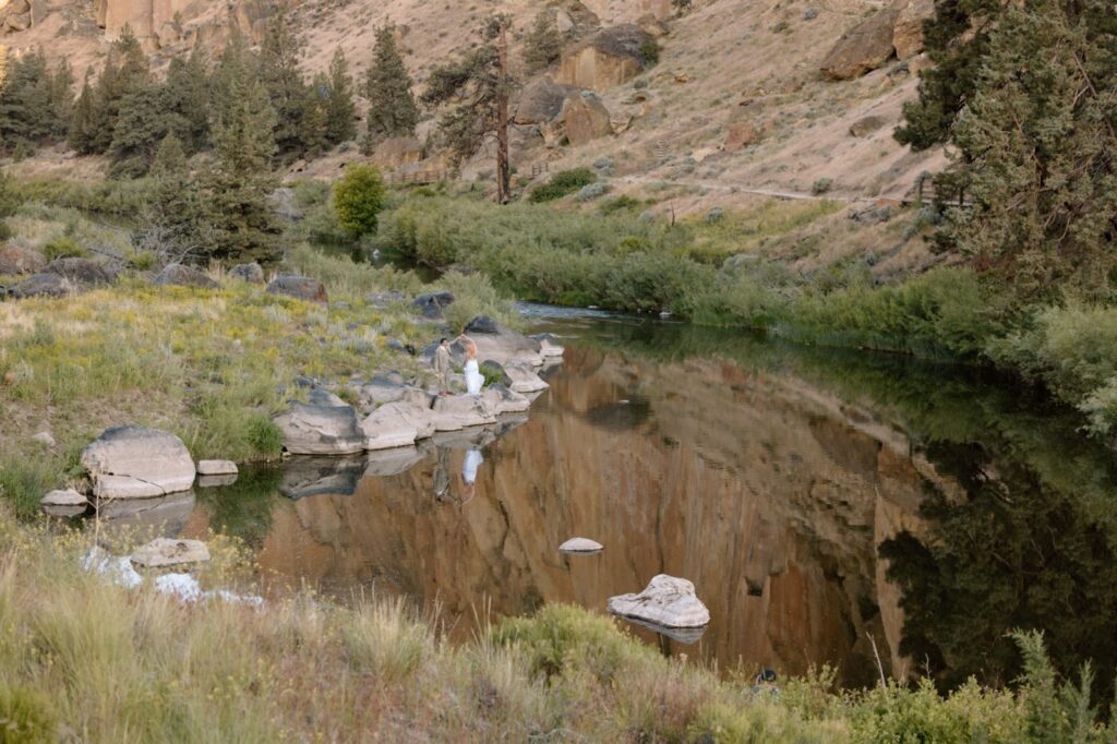 Couple spinning while standing next to reflecting water in Smith Rock State Park.