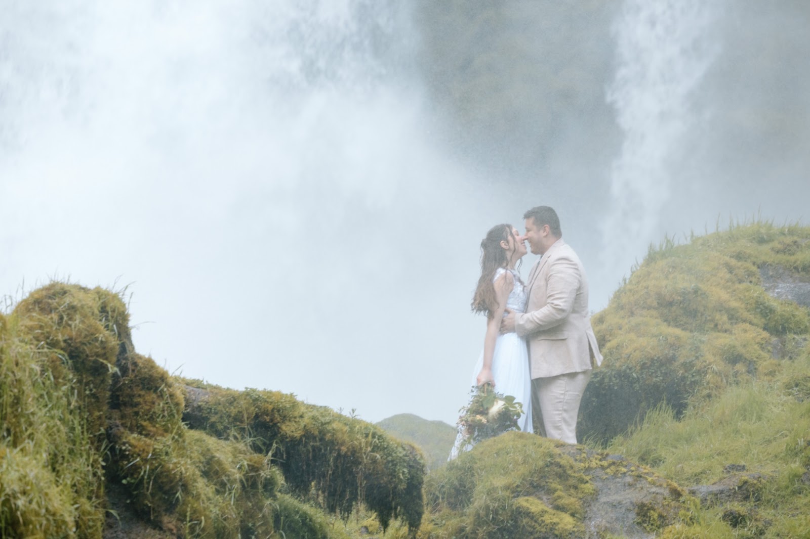 Couple surrounded by the mist of a waterfall in Central Oregon.