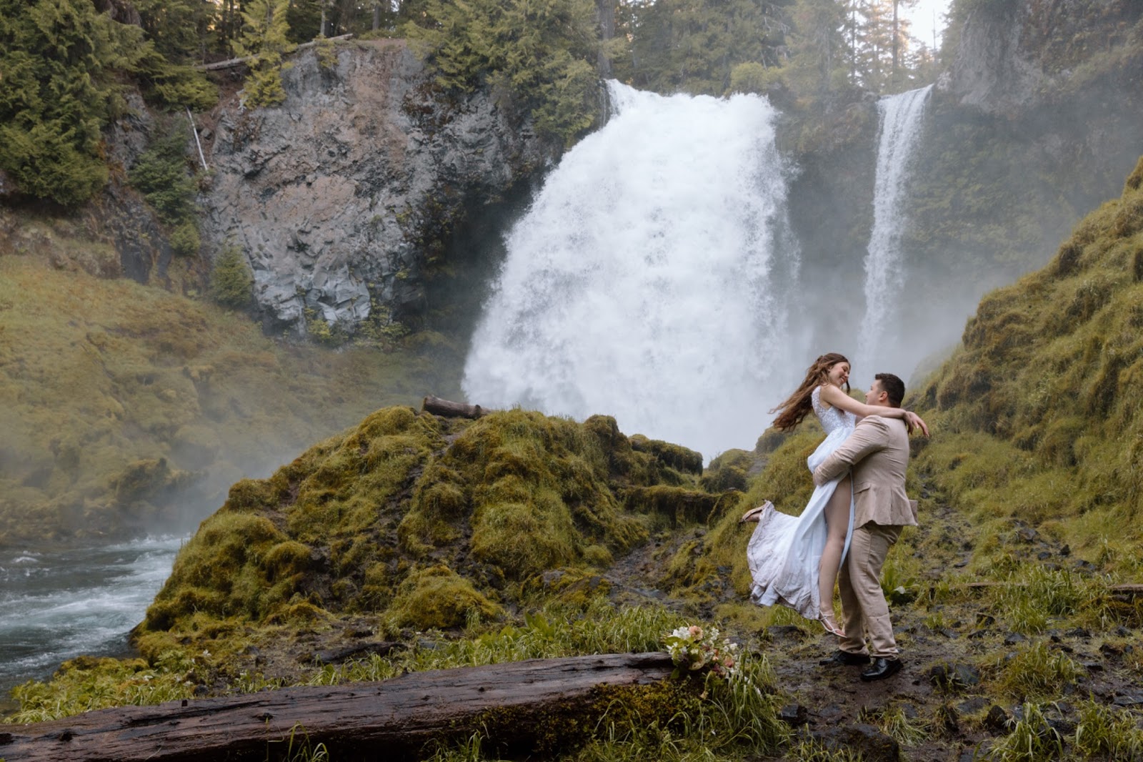 Elopement couple spinning in front of a waterfall in Central Oregon.