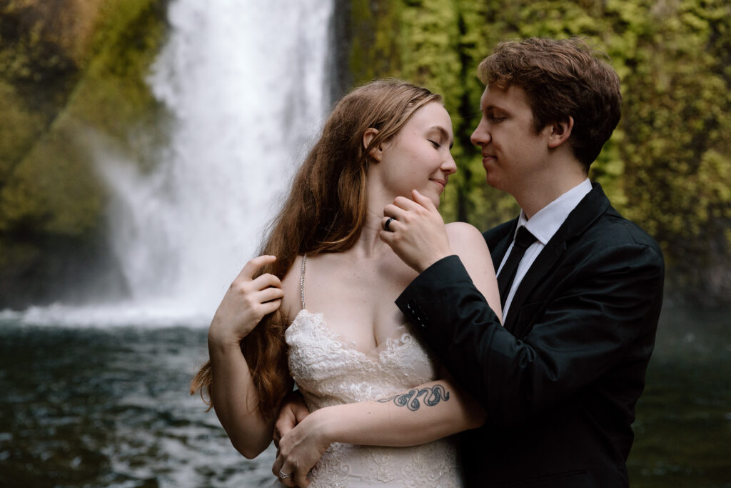 Couple embracing in front of a waterfall in the Columbia River Gorge.