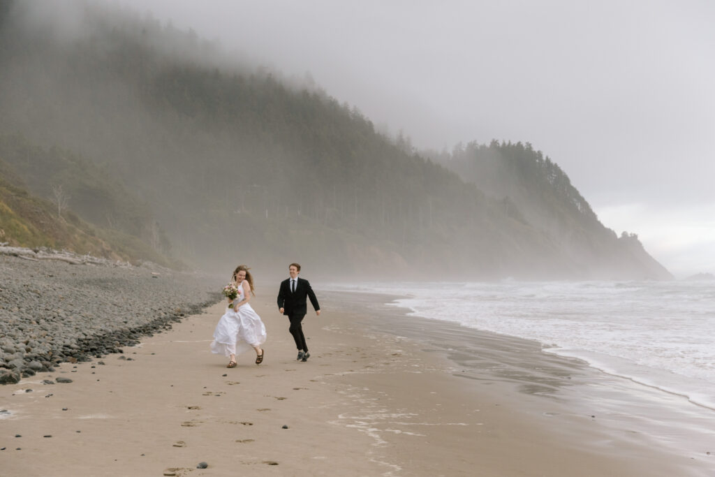 Elopement couple running on a beach on the Oregon Coast.
