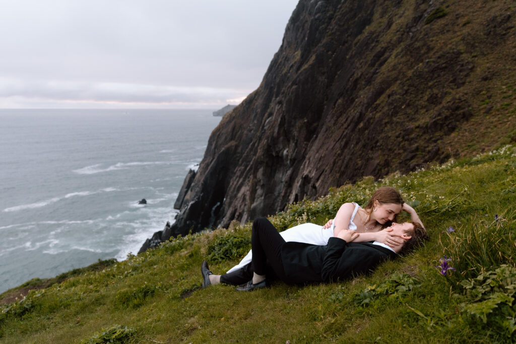 Elopement couple lying down near a cliff on the Oregon Coast.
