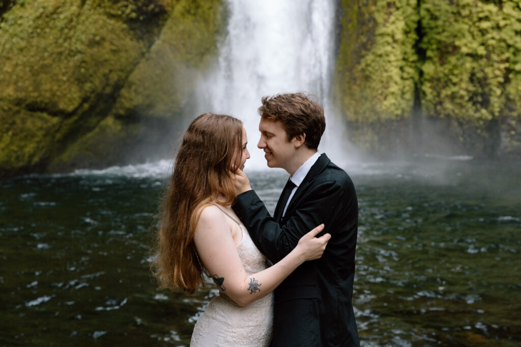 Couple leaning in for a kiss in front of a waterfall in the Columbia River Gorge.