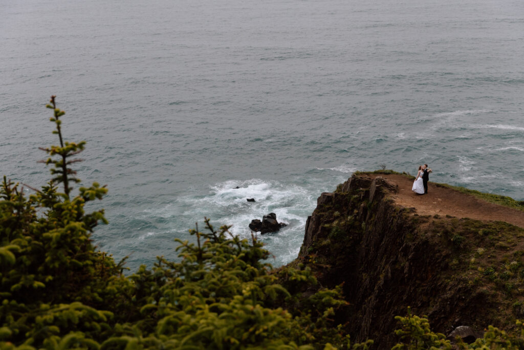 Couple at the edge of a cliff on the Oregon Coast.