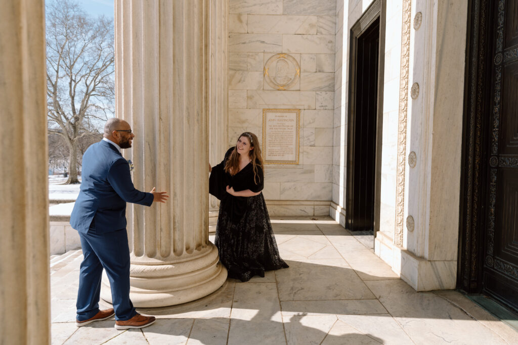 Bride and groom playing hide and seek at the entrance of the Cleveland Museum of Art. 