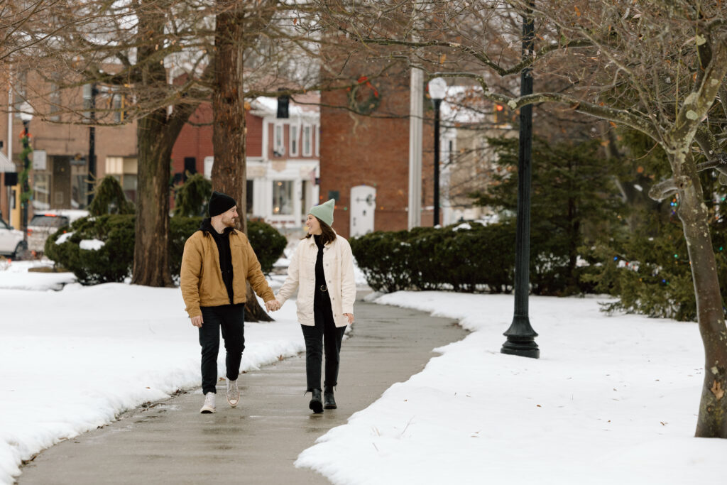 Engaged couple holding hands and walking down a path in downtown Hudson.