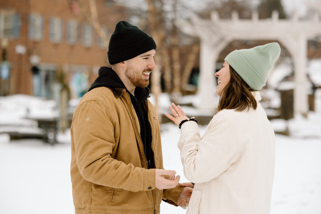 Couple laughing and talking about their engagement while admiring the ring.