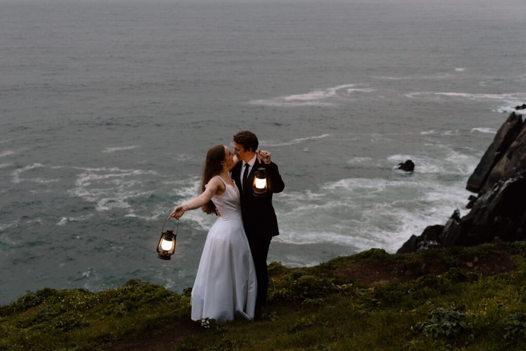 Couple holding lanterns and embracing near the cliff edge.