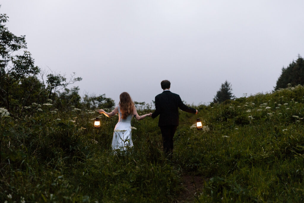 Couple walking through a field with lanterns away from the cliff.