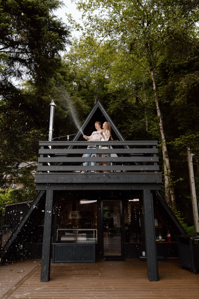 Couple popping champagne from their A-frame airbnb.