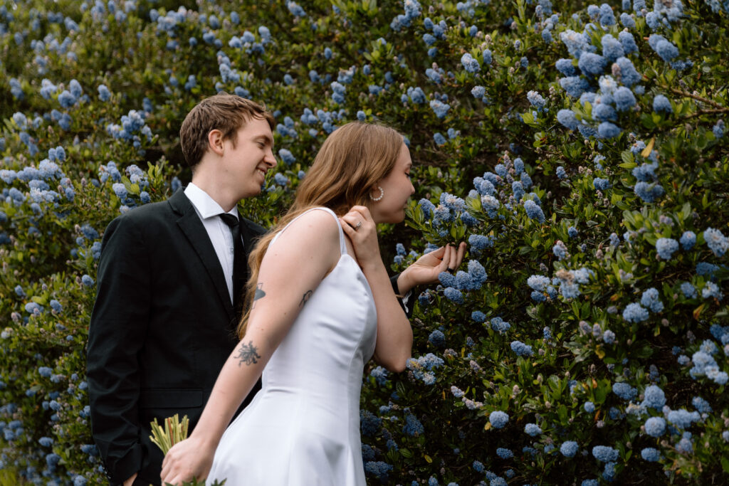 Couple sniffing purple-blue flowers.