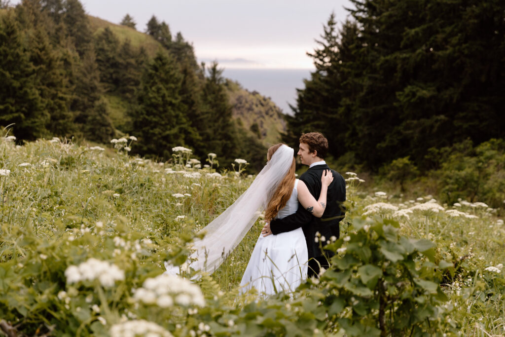 Couple embracing while walking towards a cliff viewpoint.