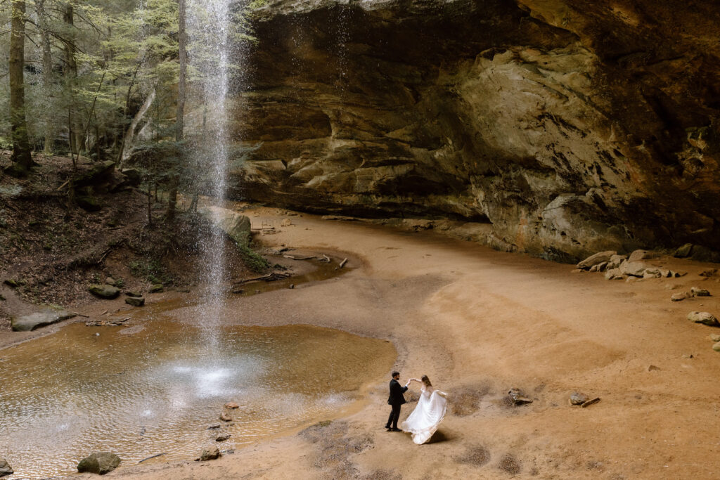 Couple dancing next to the waterfall in Ash Cave during a spring elopement.