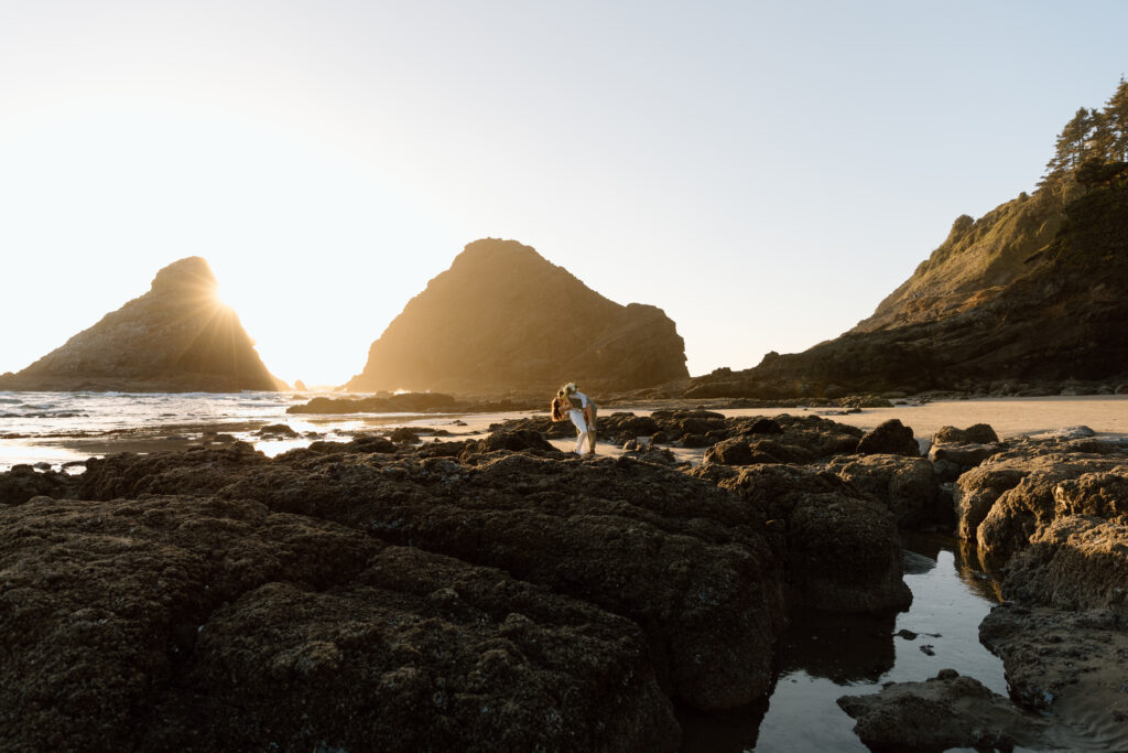 Groom dipping bride among the rocks on Heceta Head Beach.