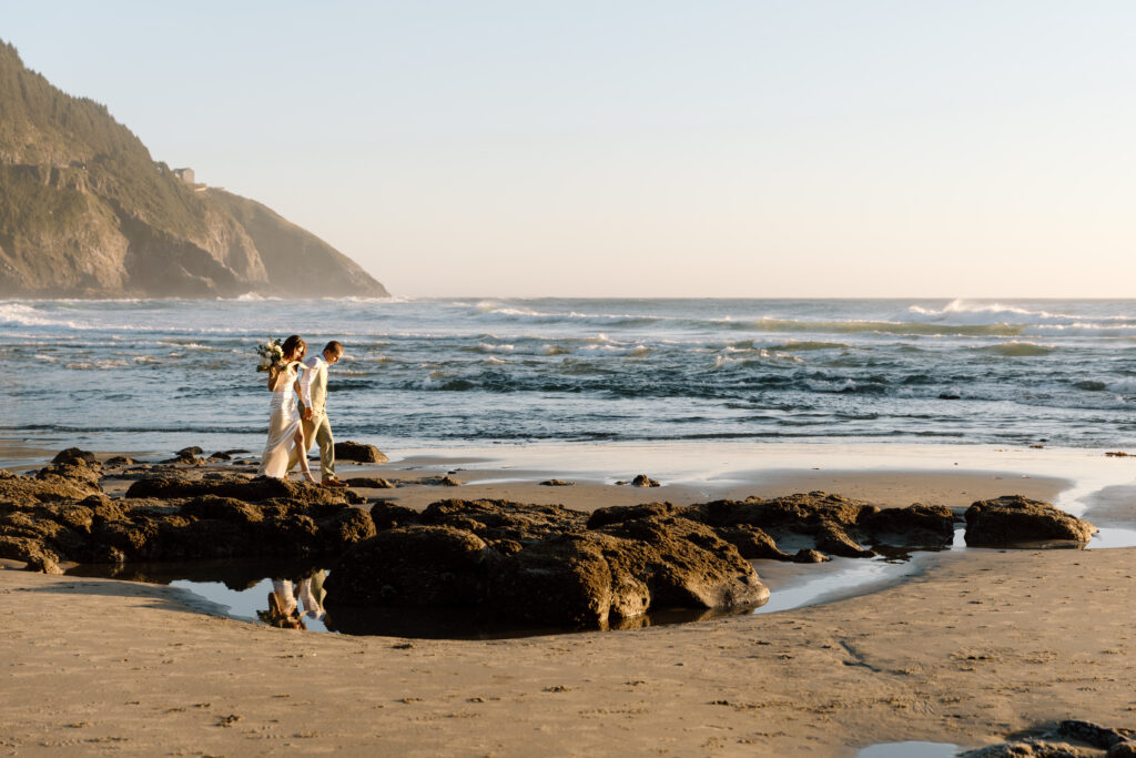 Bride and groom walking near the water on Heceta Head Beach.