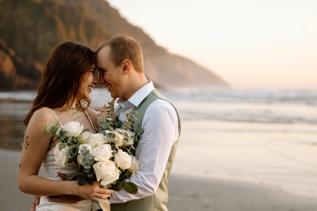 Couple leaning in close together and smiling at sunset on the Oregon Coast.