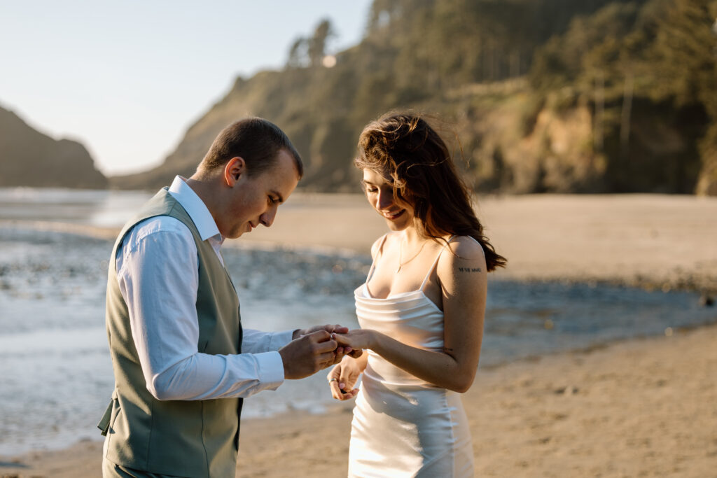 Groom putting wedding band on bride's hand.