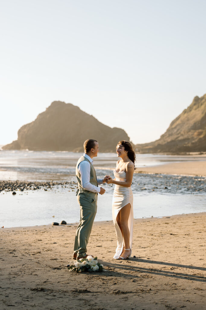 Bride and groom holding hands on Heceta Head Beach.