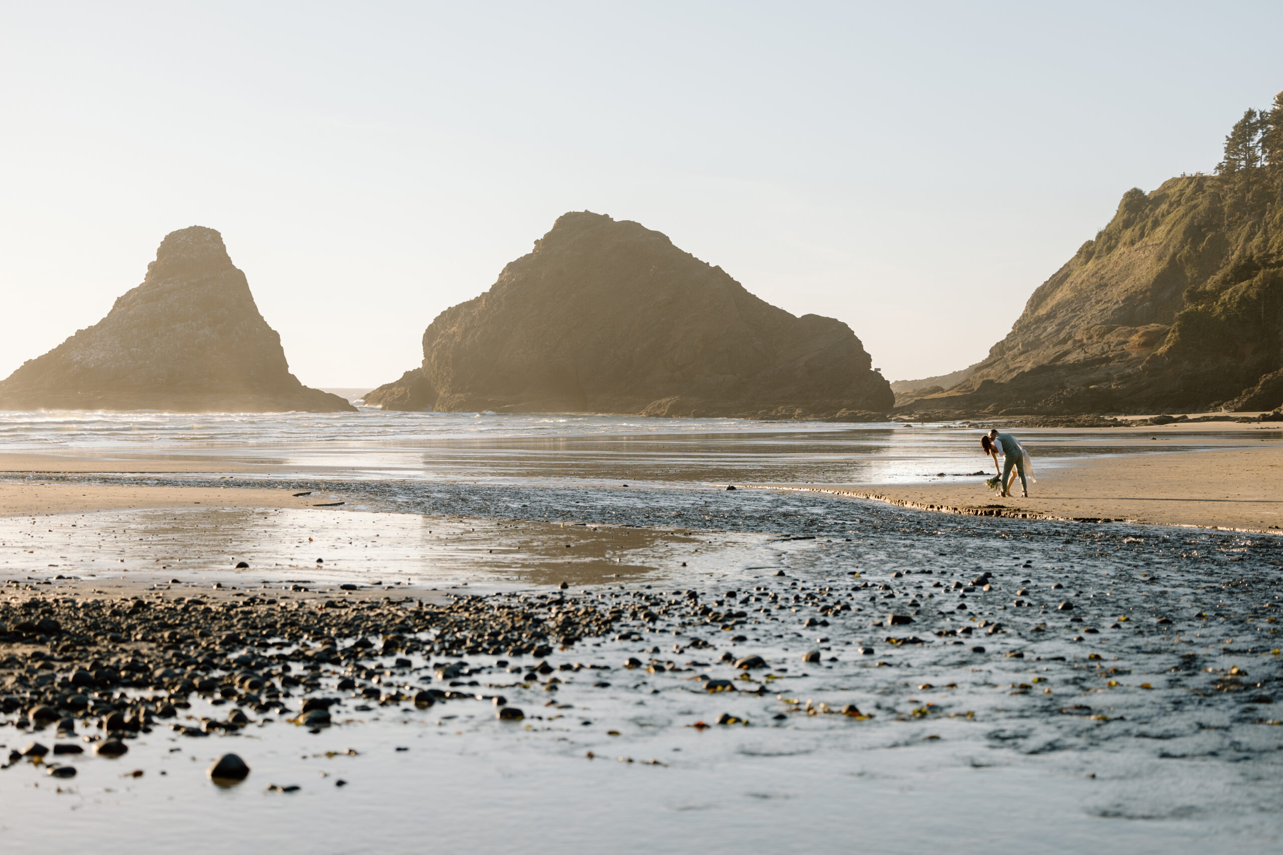 Couple kissing with water and sea stacks surrounding them.