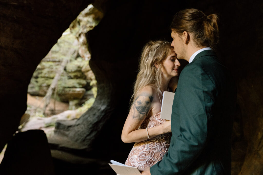 Groom kissing bride on forehead.
