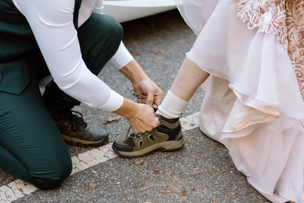 Groom tying bride's hiking boot.