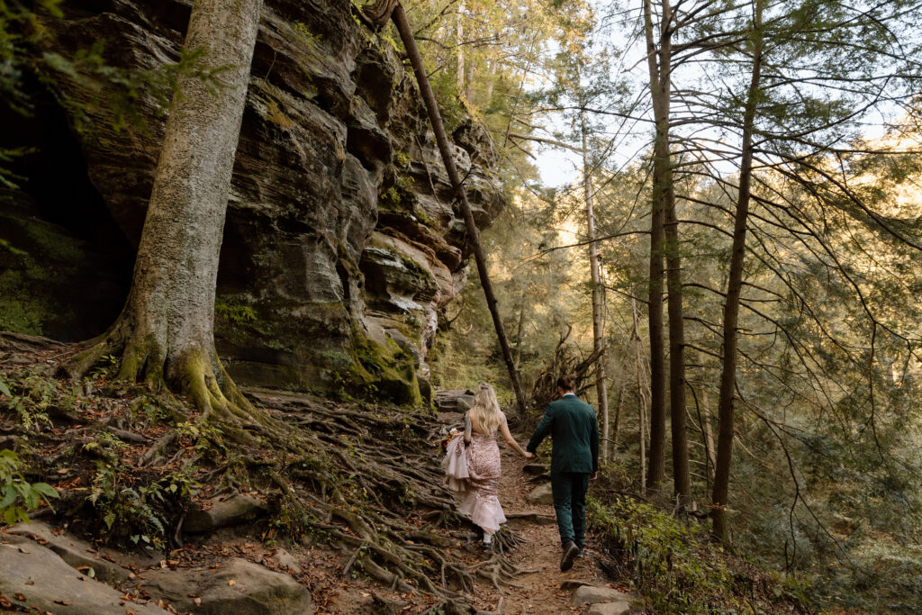Couple walking on Rock House trail next to a tree with a huge exposed root system.
