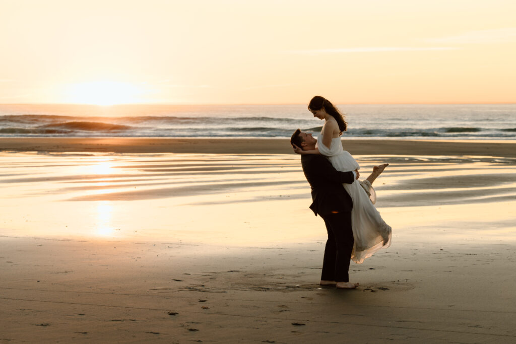Couple eloping at sunset on the Oregon Coast. The groom is lifting up and spinning the bride.