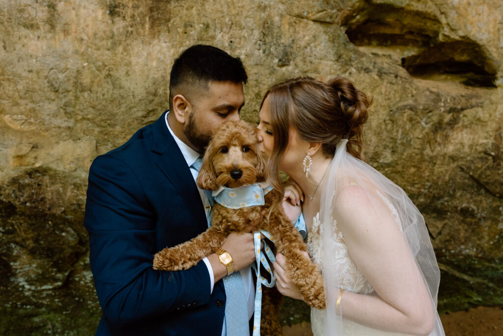 Couple kissing their dog on the cheeks