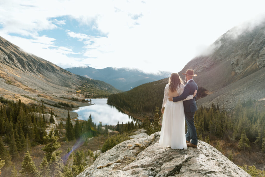 Couple embracing each other and looking out on a lake and the mountains.
