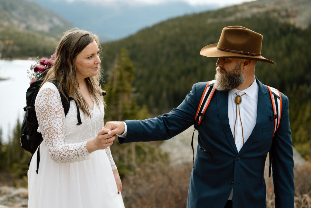 Couple holding hands and helping each other walk while hiking.
