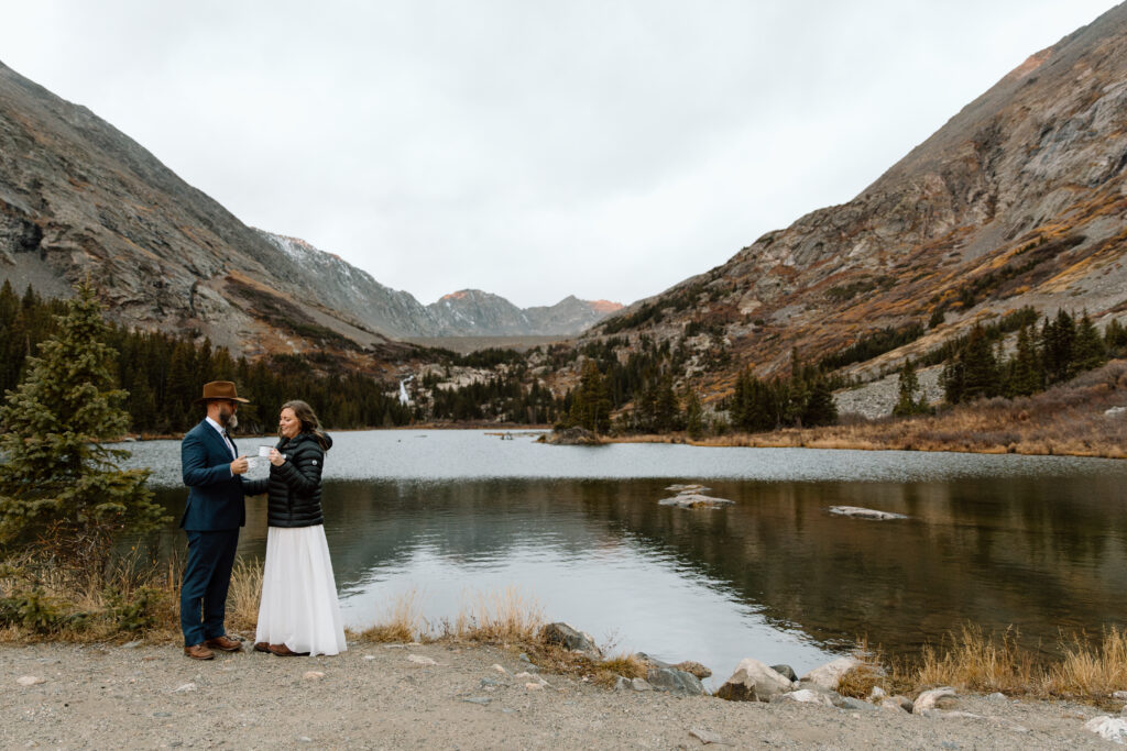 Couple sharing coffee in front of an alpine lake.