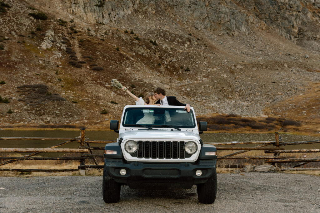 Couple kissing while standing in their jeep.