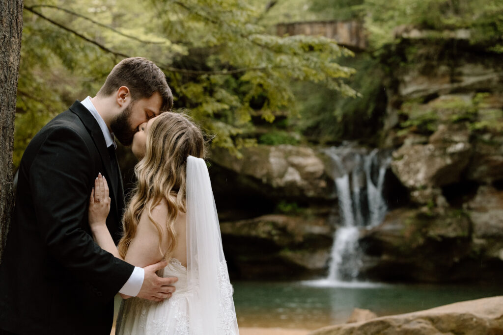 Couple kissing in front of a waterfall in Hocking Hills during a destination elopement.