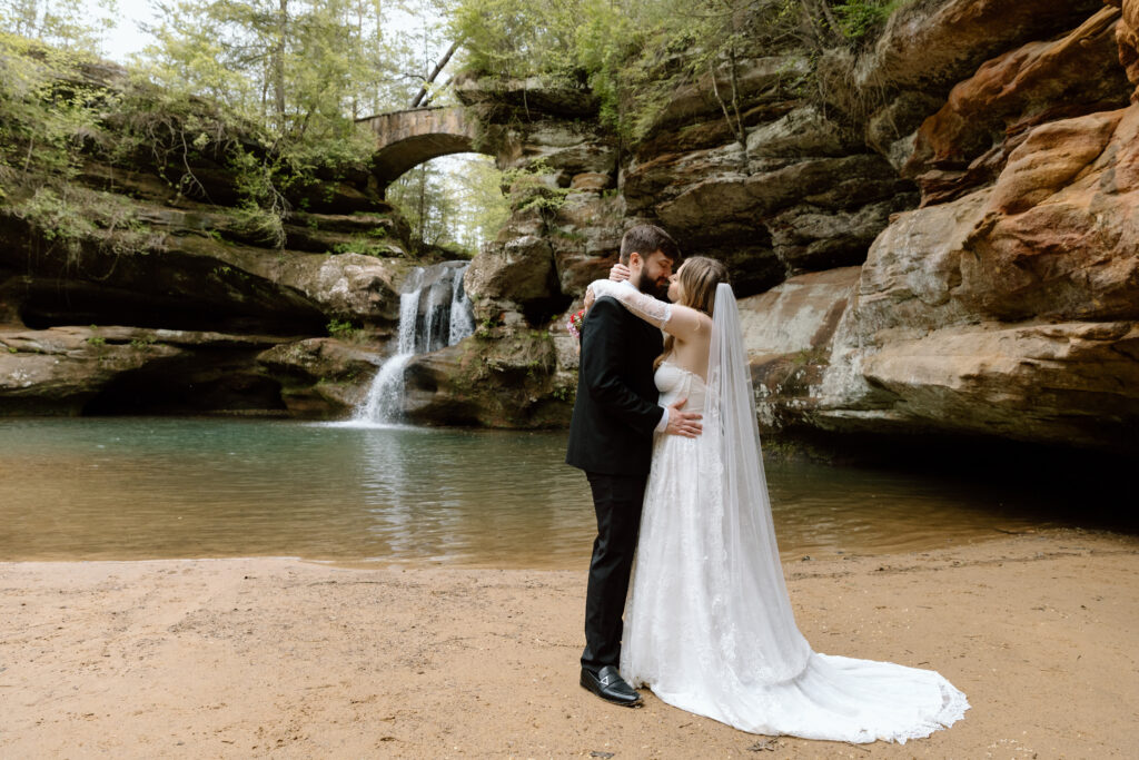 Elopement couple kissing in front of the Old Man's Cave waterfall.