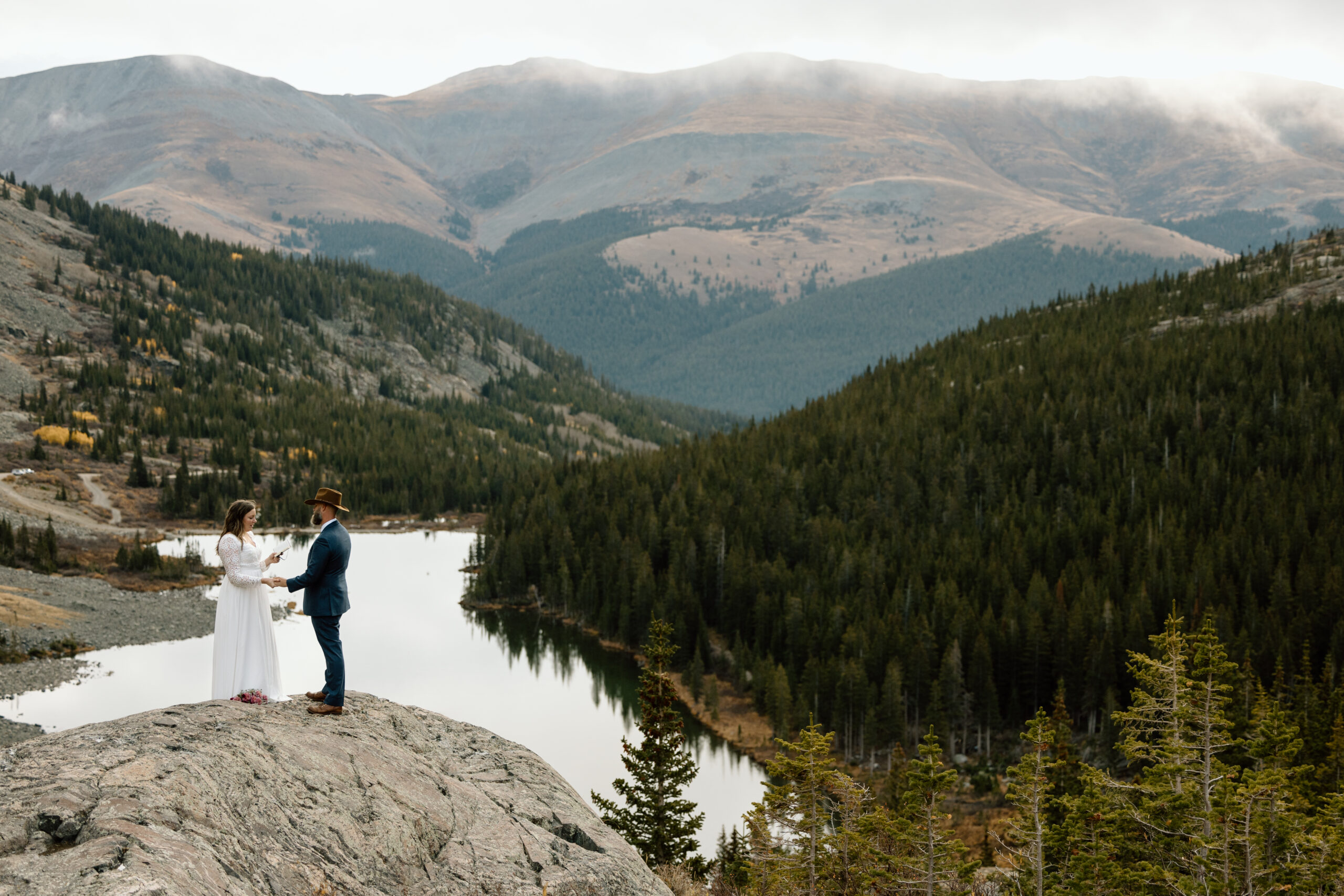 Couple on a rocky outcropping above an alpine lake.